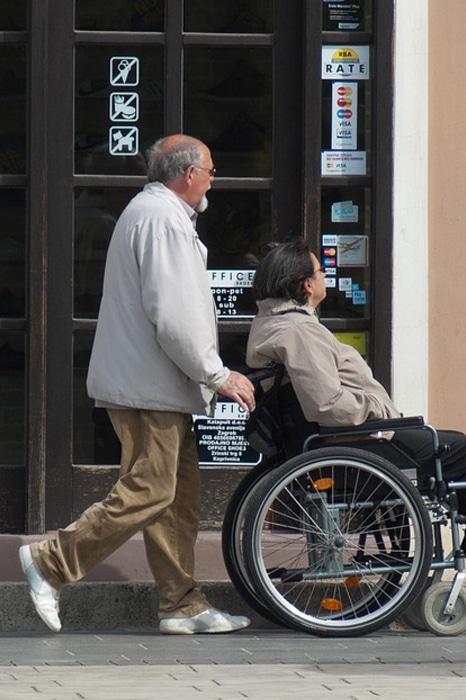A support worker pushing a wheelchair through a city street in Penrith